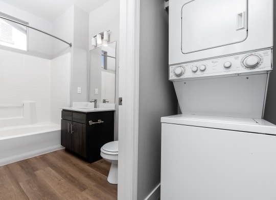 a white washer and dryer in a bathroom with a toilet and a sink