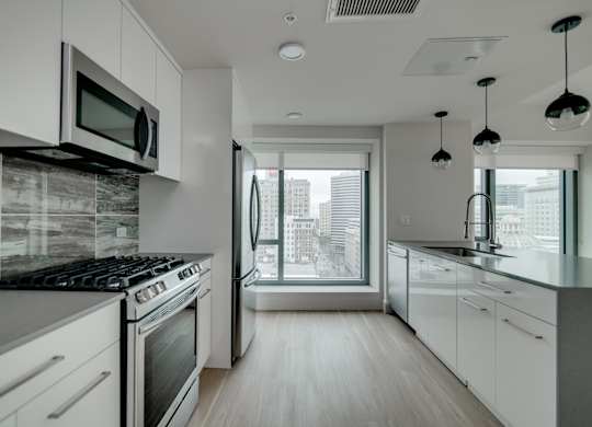 A modern kitchen with white cabinets and a black stove top.