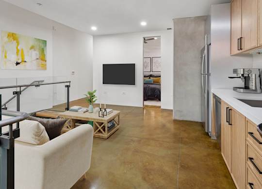 A modern kitchen with a refrigerator, sink, and a living area with a couch and a coffee table.