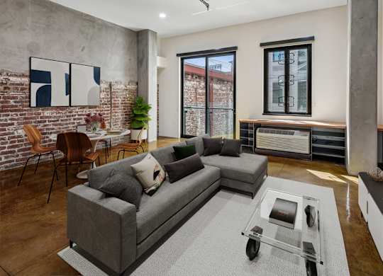 A modern living room with a grey couch and a glass coffee table.