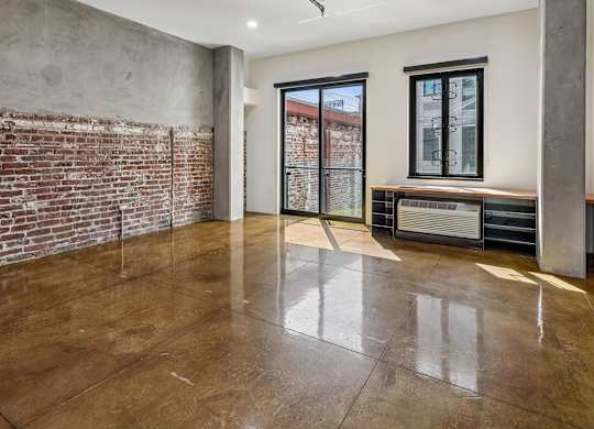 A room with a brown floor and a brick wall.