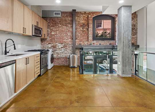 A kitchen with a brick wall and wooden cabinets.