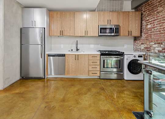 A kitchen with a refrigerator, microwave, oven, and sink.