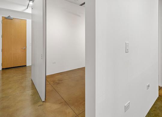 A white wall with a switchboard and a brown door.