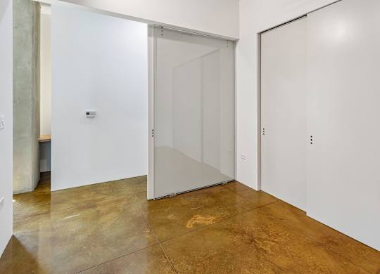 A room with a white door and a brown floor.