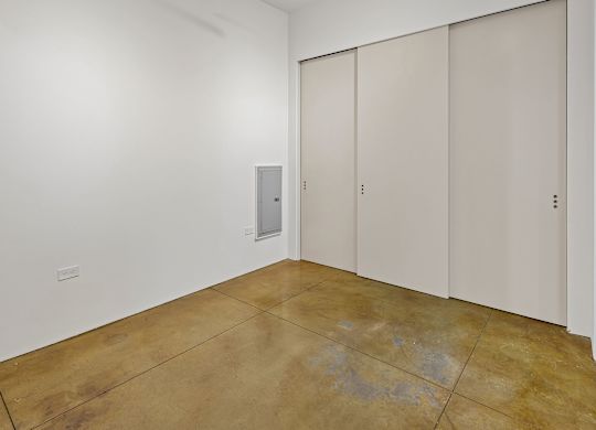 A room with a brown floor and white walls with three doors.
