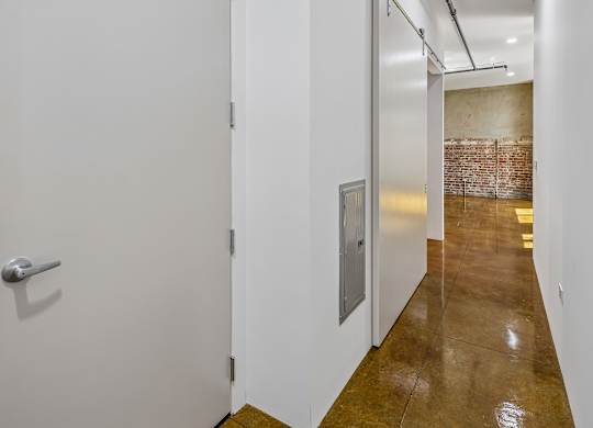 A hallway with a white door and a brick wall in the background.