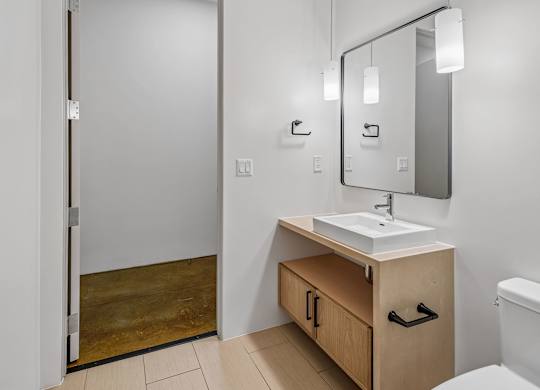 A bathroom with a sink, mirror, and toilet.