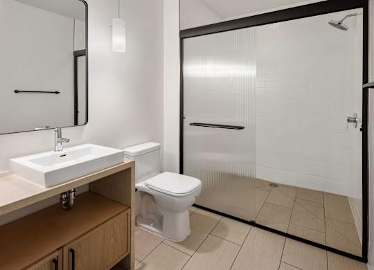 A white toilet is in a bathroom with a sink and mirror.