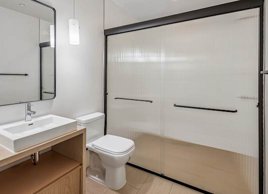 A white toilet sits in a bathroom next to a sink and a mirror.