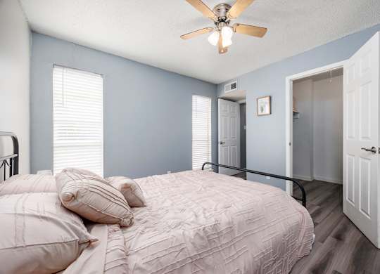 A bedroom with a bed, pillows, and a ceiling fan.