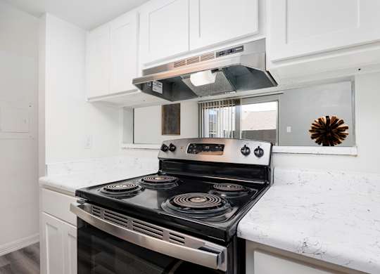 A modern kitchen with a stove top oven and white cabinets.