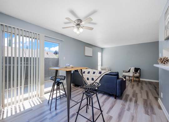 A living room with a blue couch and a dining table with chairs.