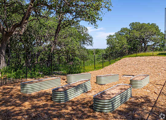A row of green water tanks are lined up on a dirt field.