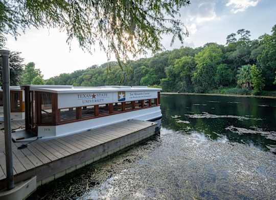 A Texas State University boat is docked at a pier.