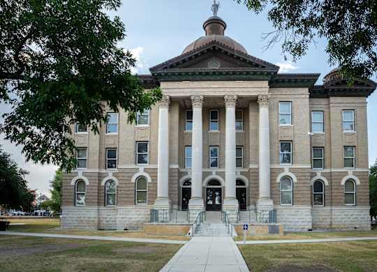 A large, stately building with a dome and columns stands under a clear sky.