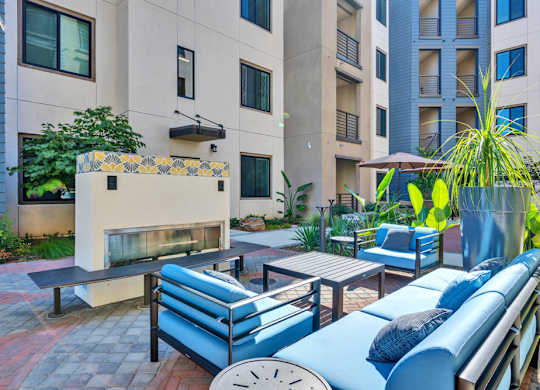 A patio with blue couches and a fireplace.