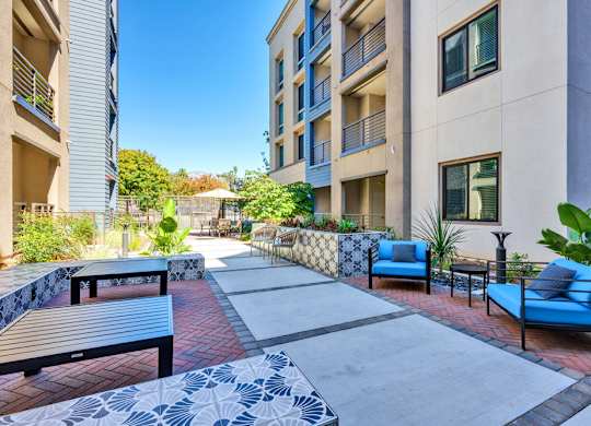 A patio area with blue couches and a brick floor.