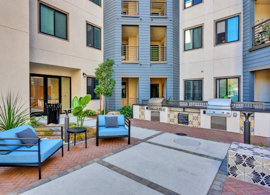 A patio with a blue couch and a table with a plant on it.