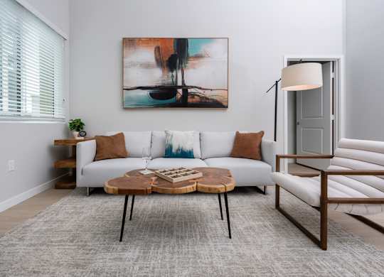 A living room with a white couch, a coffee table, and a painting on the wall.