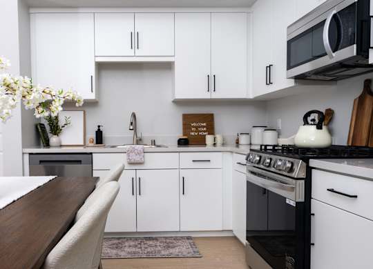 A kitchen with white cabinets and a wooden table.