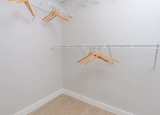Three wooden hangers are hanging on a white wall.