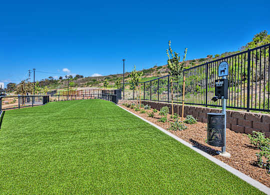 A green lawn with a fence and a sign on it.