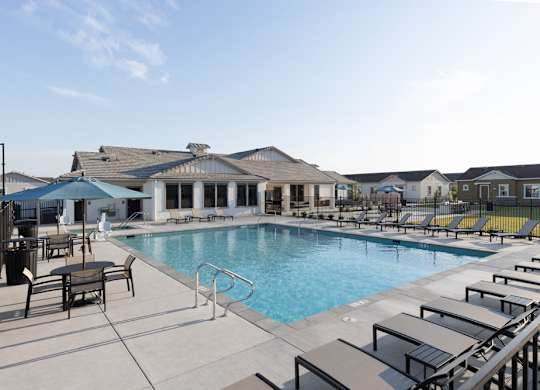 A pool area with sun loungers and a building in the background.