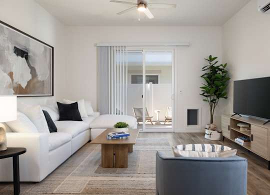 A living room with a white sofa, a coffee table, and a television.