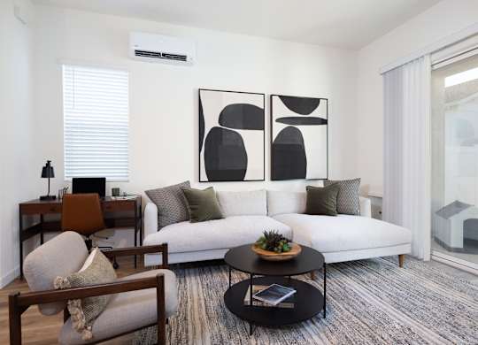 A modern living room with a white couch, a coffee table, and a large abstract painting on the wall.