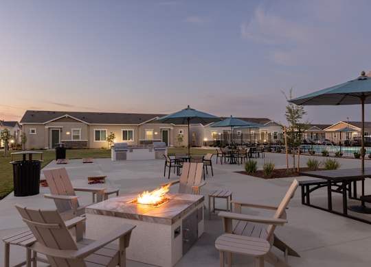 A fire pit is surrounded by chairs in a courtyard.