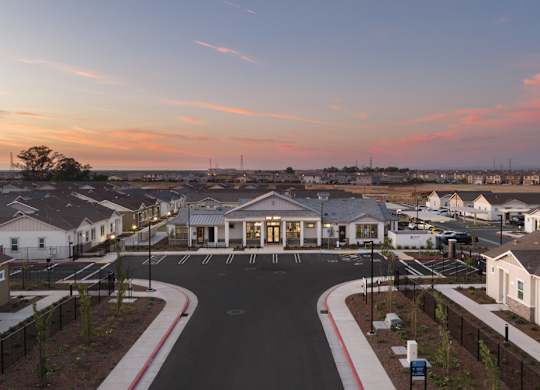 A sunset view of a residential area with houses and a central building.