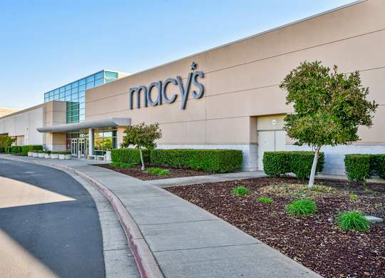 The exterior of a Macy's store with a clear blue sky in the background.