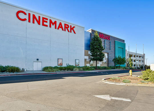 A Cinemark movie theater is shown with a red sign on the building.