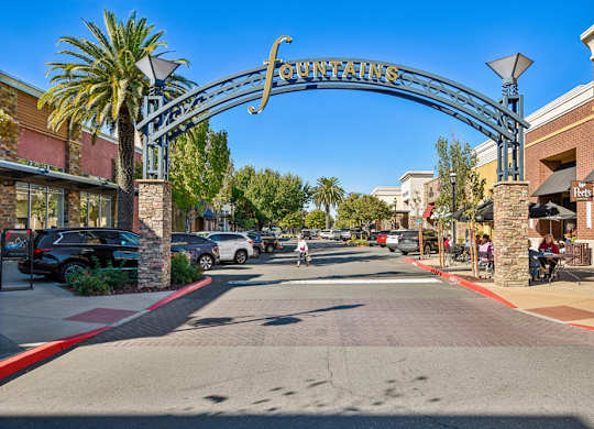 A street view of a shopping area with a sign that reads