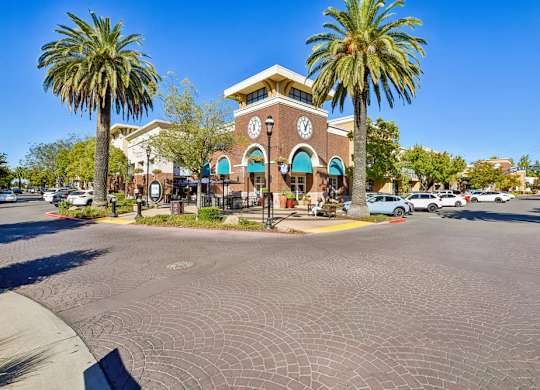 A clock tower is in front of a building with palm trees.