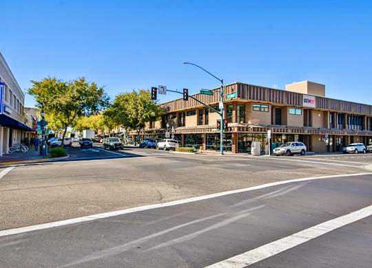 A street view with a building on the right and cars on the road.