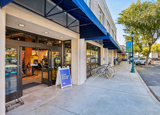 A street view of a storefront with a blue awning and a sign that reads