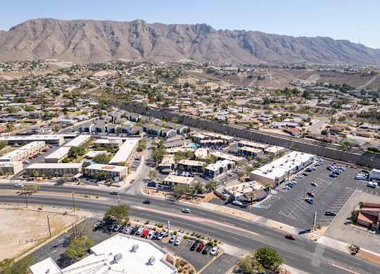 A parking lot is surrounded by buildings and a mountain in the background.