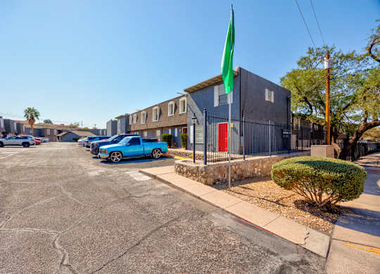 A parking lot with cars and a building with a green flag.