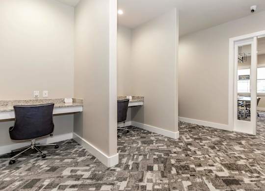 A room with a carpeted floor and a desk with a chair.