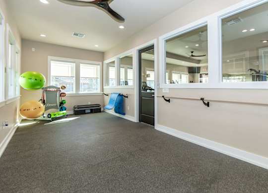 A room with a grey carpet and a ceiling fan.