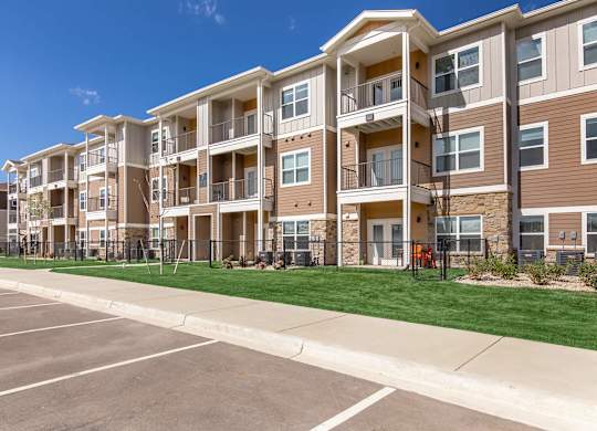 A large apartment complex with a parking lot in front.