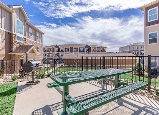 A green picnic table is in the foreground of a residential area.