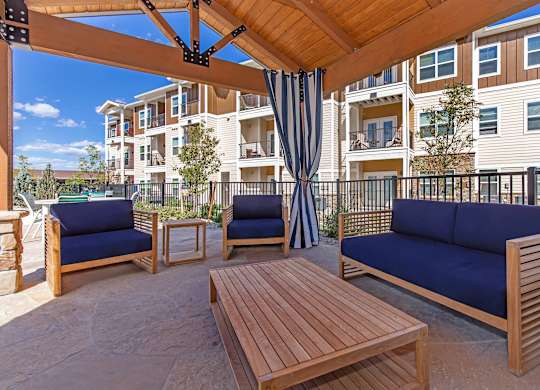 A wooden patio with blue cushions and a table.