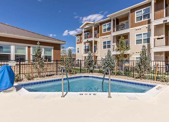A pool in front of a building with a blue chair.