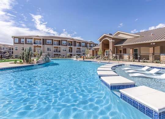 A large swimming pool with a blue tiled edge and white sun loungers.