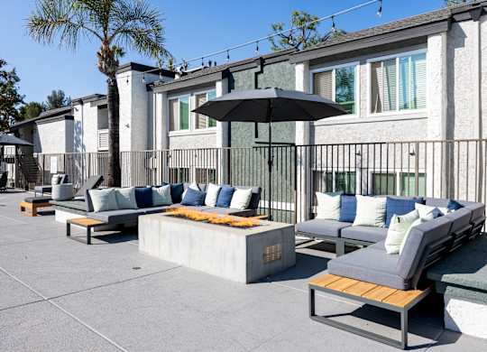 A patio with a black umbrella and grey couches at Verandas Apartments, West Covina, CA, 91791