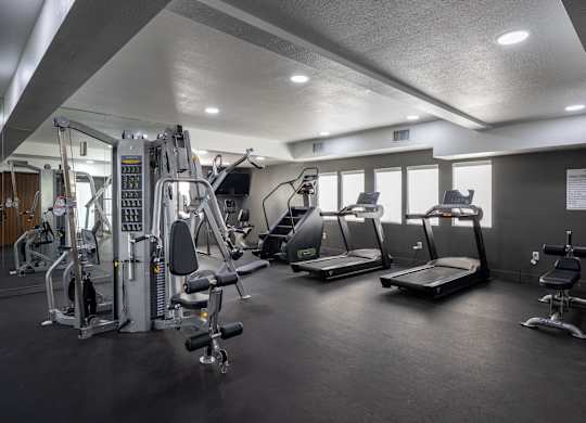 A gym with a variety of equipment including treadmills, weights, and a bench press at Verandas Apartments, West Covina, 91791