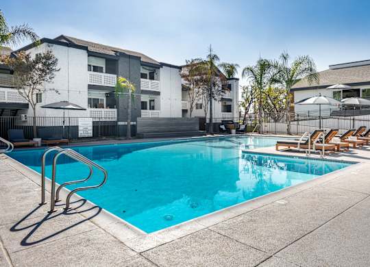 A swimming pool with a blue tinted water and sun loungers at Verandas Apartments, West Covina, 91791